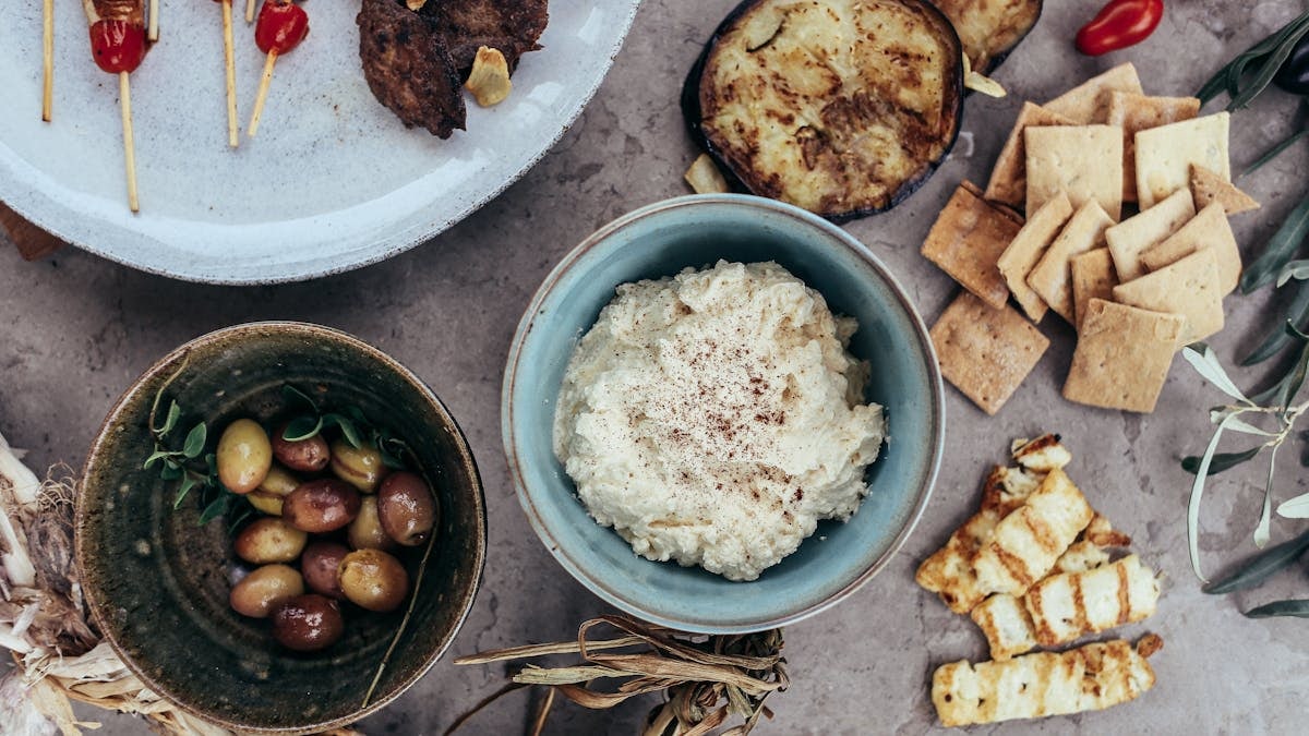 A variety of Mediterranean appetizers featuring hummus, olives, and grilled vegetables set on a rustic table.